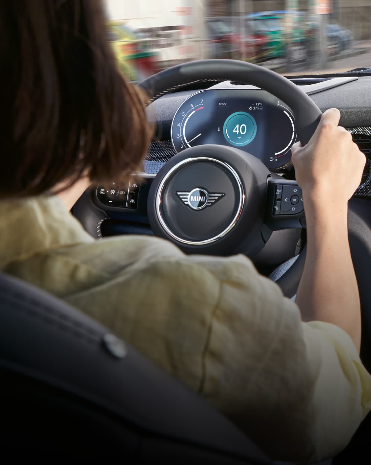 Back view of a person in a green shirt holding onto the multifunctional sport leather steering wheel in a MINI Hardtop 2 Door.